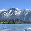 The image showcases a breathtaking view of a snow-capped mountain towering over a forest and a sparkling blue lake, all under a clear sky.