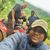 A group of four people poses happily for a selfie on an ATV adventure in a lush green landscape.