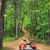 A red all-terrain vehicle is parked at the start of a winding dirt trail surrounded by a dense green forest.