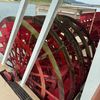 The image shows a large red paddle wheel of a riverboat, viewed from a higher deck with a lake and hills in the background.