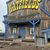 The image shows a rustic wooden building with a large sign that reads 