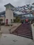 The image shows the entrance of the San Antonio Zoo with a large, topiary-like gorilla statue positioned on the staircase and colorful butterfly sculptures overhead.