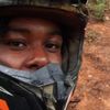 A group of people are enjoying an off-road adventure on ATVs in a forested area, with one of them taking a selfie.