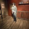 A lifelike figure dressed in traditional Western attire stands next to a 