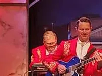 A band performs on stage, with members playing various instruments, and one seated in a wheelchair, as part of the Presleys' Country Jubilee.