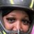 A person wearing a helmet takes a selfie during a break in an off-road ATV adventure in a dusty, forested area.