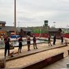 A group of people is engaged in axe throwing at an outdoor recreational facility with a rustic, camp-like atmosphere.