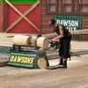 A person is operating a chainsaw to cut through a log, likely at an outdoor lumberjack show or competition.