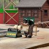 A person in protective gear is using a chainsaw on a log at a woodcutting demonstration or competition.