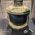 The image shows an old, corroded starboard navigation light with a wick and wick holder, likely recovered from a sunken vessel, displayed in a museum setting.