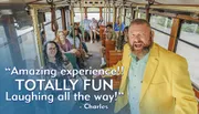 A jovial man in a yellow jacket is enthusiastically addressing passengers in a trolley-style vehicle, with a quote bubble indicating a positive and amusing experience, as passengers in the background exhibit a mix of smiles and neutral expressions.