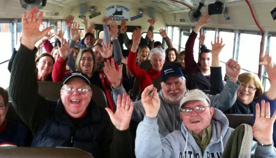 A group of cheerful people are waving and smiling inside a bus.