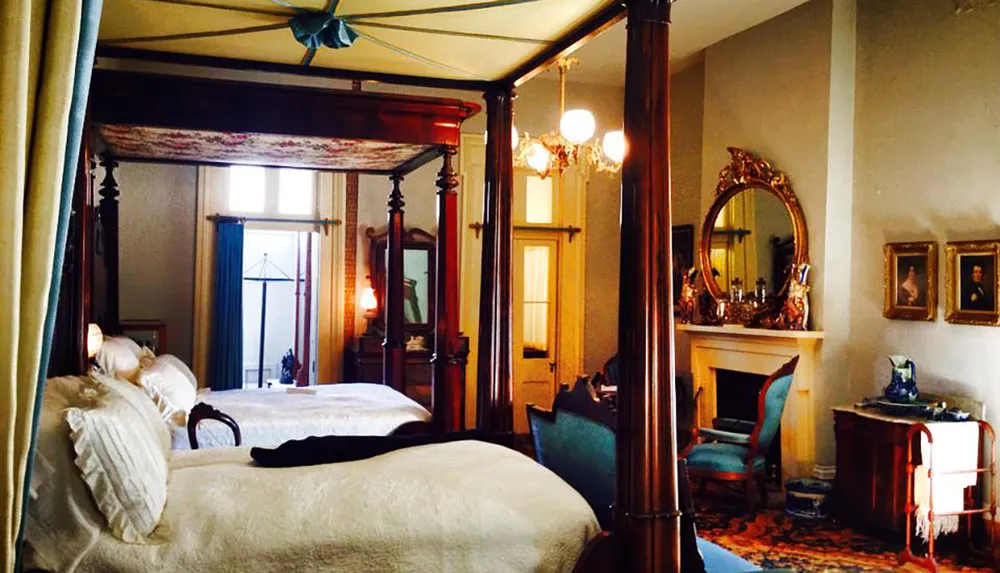 An elegantly furnished vintage bedroom with a four-poster bed ornate gold mirror chandelier and classic decorations reflecting an old-fashioned style