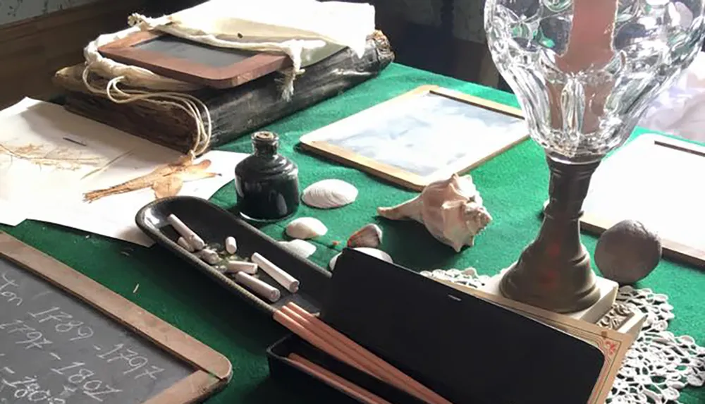 The image depicts a vintage desk setup with items like a quill inkwell chalkboard old books and seashells suggesting a historical or educational theme