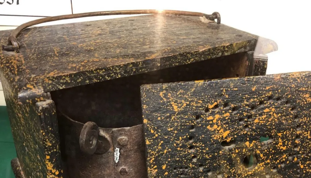 The image shows a weathered and rusted metal object with flaking yellow paint possibly a piece of industrial or agricultural equipment