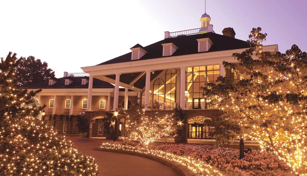 The image depicts a stately building adorned with warm twinkling lights giving it a festive and welcoming atmosphere likely during the evening