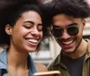 Two happy young people are looking at a smartphone screen together on a sunny day