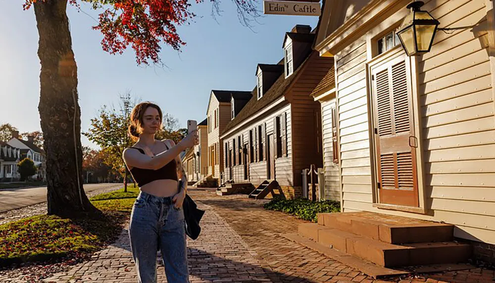 A person is taking a selfie on a sunny street lined with historical buildings