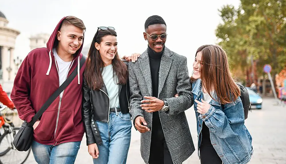 Four friends are walking and laughing together on a city street seemingly enjoying each others company