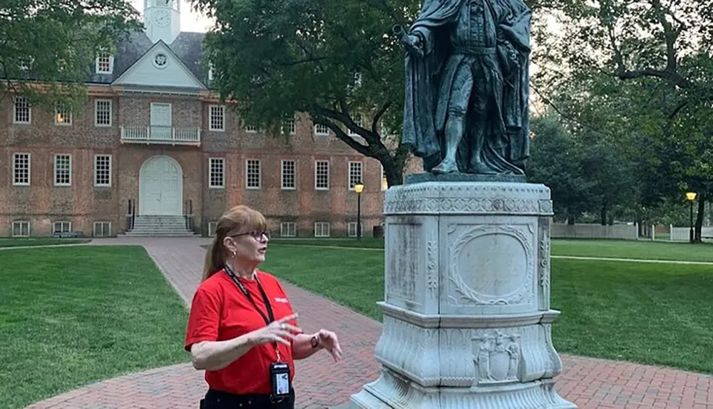 A person is giving a tour or presentation next to a statue with a historical building in the background