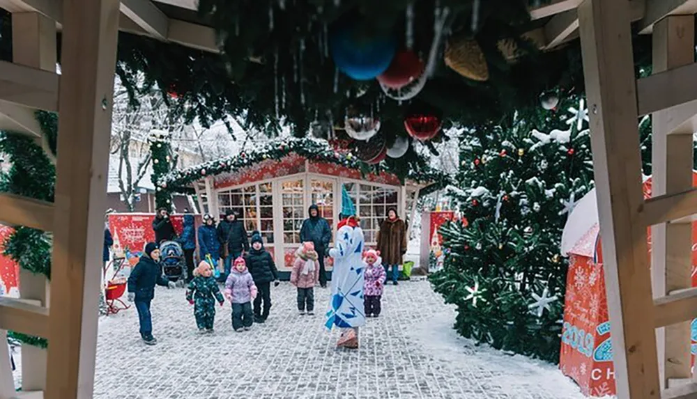 A festive winter scene at a Christmas market with people a person in a costume and holiday decorations