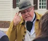 Two people dressed in historical military costumes are participating in an outdoor community event with a crowd that includes children playing