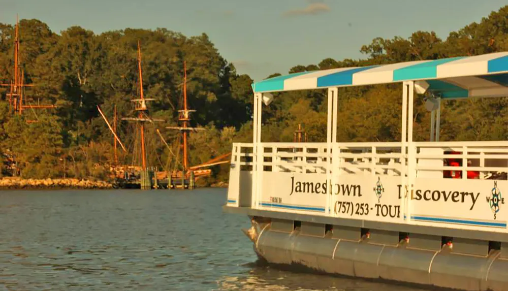 The image shows a boat labeled Jamestown Discovery on the water with a forested shore and tall ship masts visible in the background