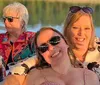 Three women are smiling and enjoying a sunny day on a boat with drinks