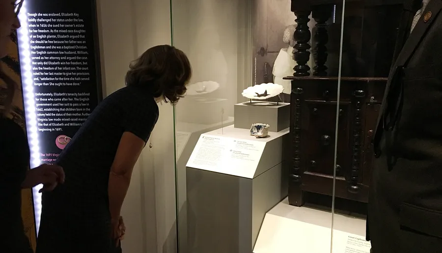 A person is observing an exhibit that includes historical artifacts and informational text in a museum display case.