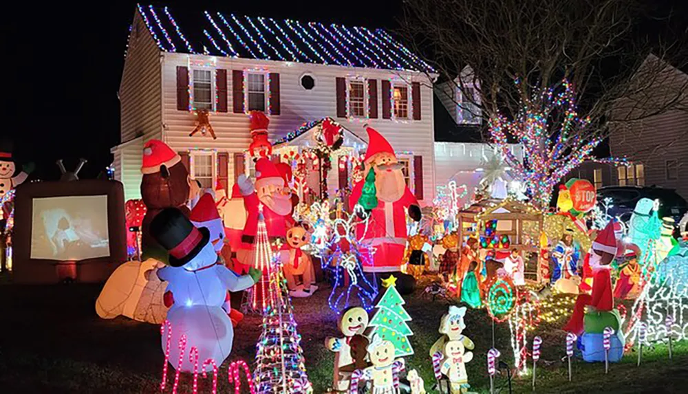 The image shows an elaborately decorated house for Christmas with numerous colorful lights inflatable characters and figures that create a festive and vibrant holiday scene