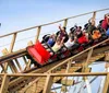 Two children are exuberantly raising their arms and yelling with joy while riding a roller coaster