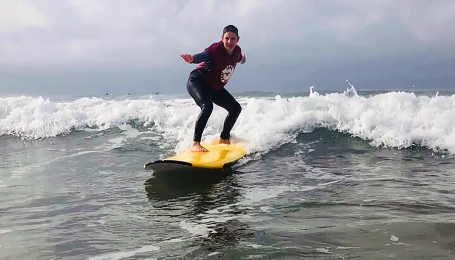 A person is surfing a small wave close to the shore.