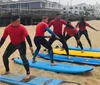 A group of people in wetsuits is practicing surfing stances on surfboards placed on the beach