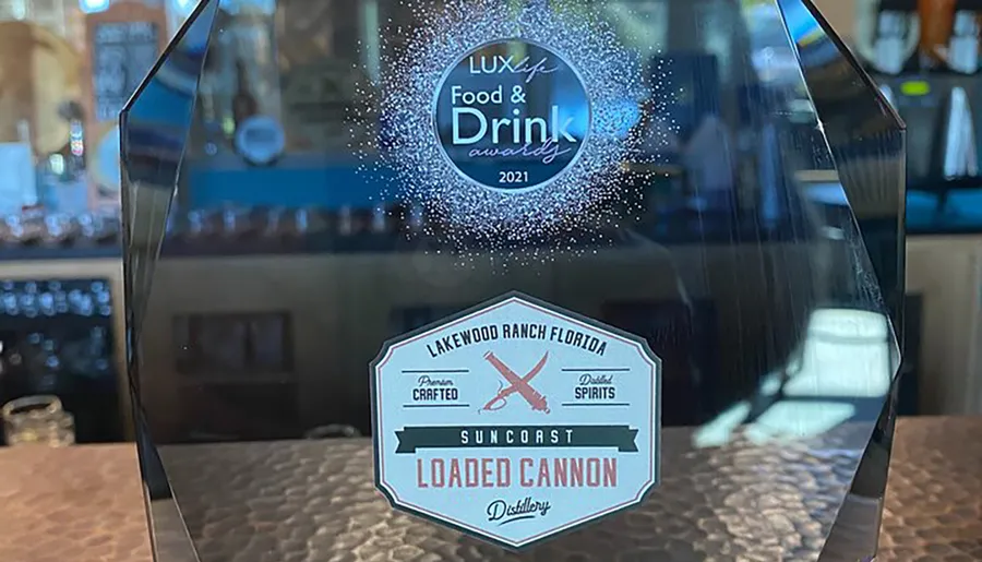 The image shows a transparent award with text indicating it is a LUXlife Food & Drink Award for 2021, presented to Suncoast Loaded Cannon Distillery in Lakewood Ranch, Florida.