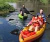 A family is enjoying a kayaking trip on a calm river with a man solo in a green kayak and a woman and two children sharing a yellow kayak