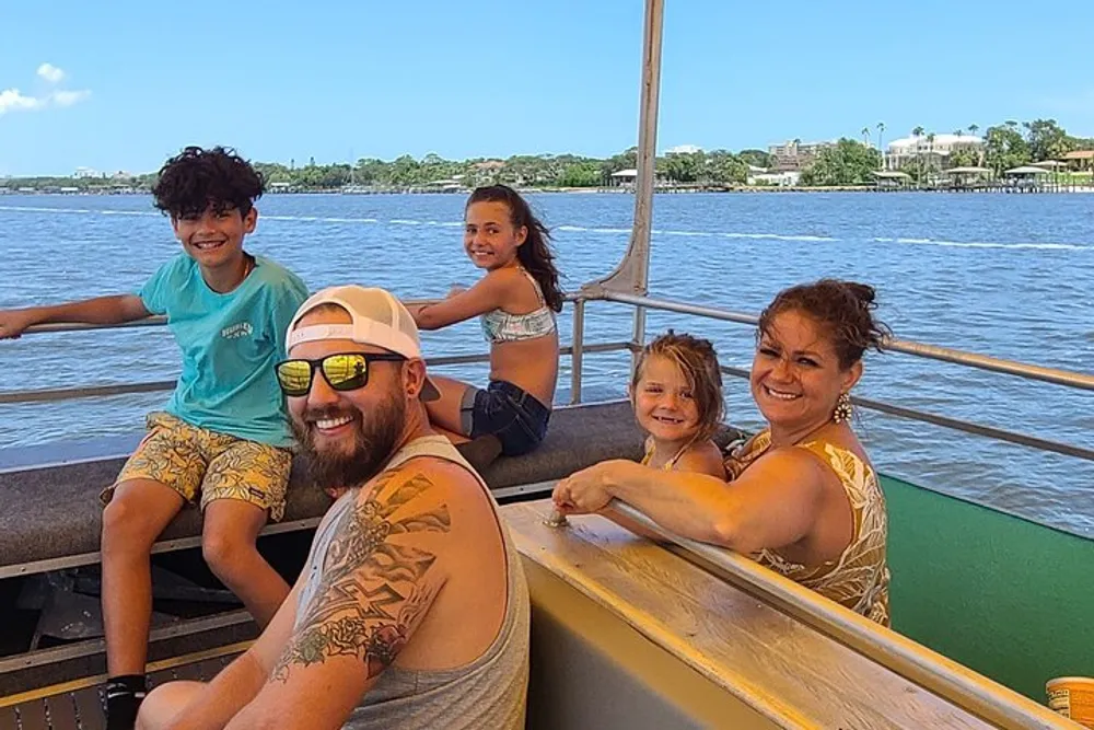 A happy group of people presumably a family is enjoying a sunny boat ride with a scenic water backdrop