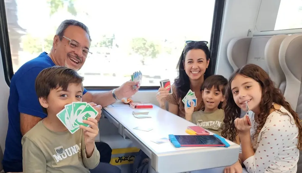 A happy family is playing Uno together on a train ride