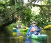 Two people are kayaking along a peaceful tree-lined waterway enjoying the outdoors