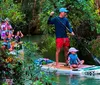 A group of people is enjoying paddleboarding and kayaking along a serene forest-lined waterway