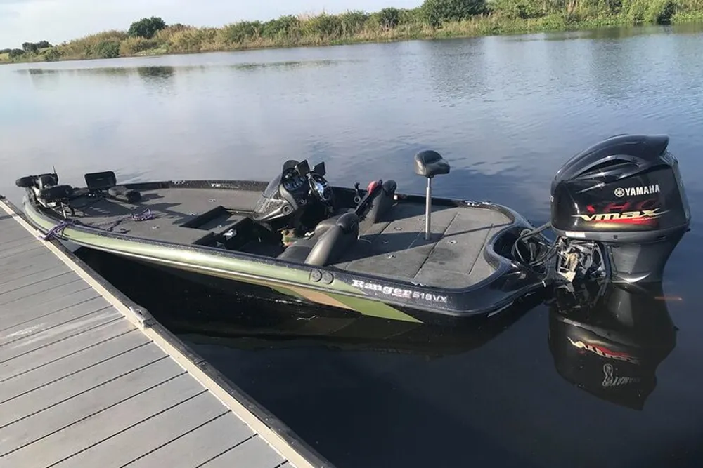 A black and green Ranger bass boat equipped with a Yamaha outboard motor is docked on a calm river with a lush riverbank in the background