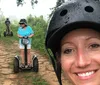 A group of people are enjoying a Segway tour on a forest trail with a smiling woman in the foreground taking a selfie