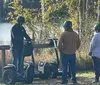 A group of people are enjoying a Segway tour on a forest trail with a smiling woman in the foreground taking a selfie