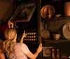 Two individuals are looking at or searching for something in a dark rustic cupboard filled with antique objects and crockery