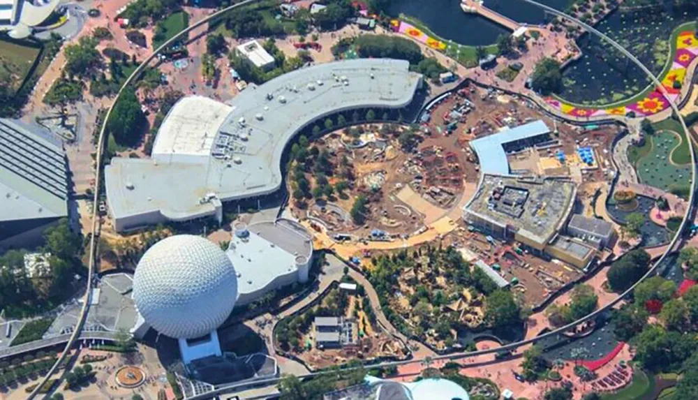 This aerial image shows a distinctive geodesic sphere and the surrounding area under construction at a theme park resort