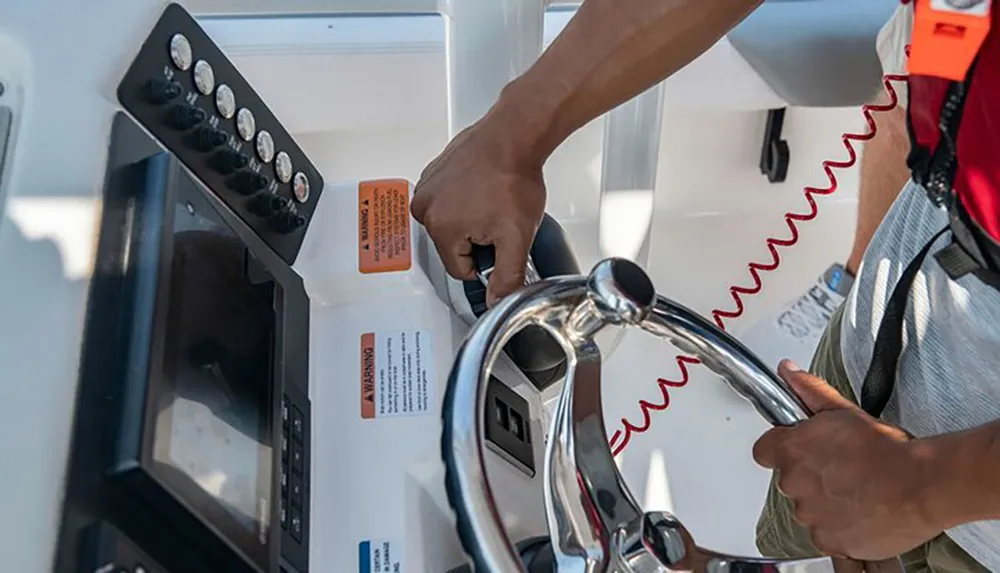 A person is steering a boat and manipulating the throttle control