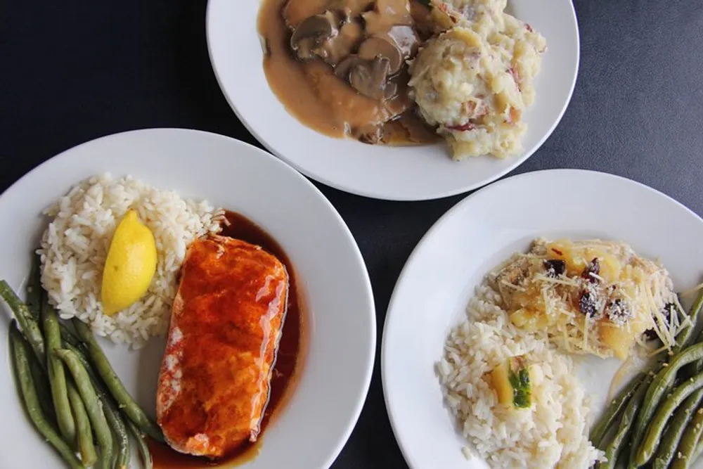 The image shows three plates of food each with a protein a side of rice and green beans or mashed potatoes suggesting a well-balanced meal