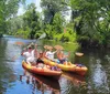 A group of people are kayaking down a serene waterway flanked by lush greenery