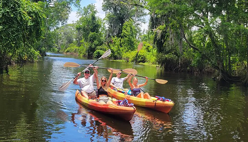 A group of people are kayaking down a serene waterway flanked by lush greenery