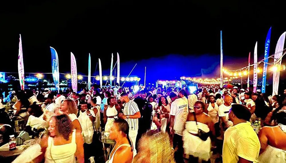 A lively outdoor event at night where attendees are dressed predominantly in white apparel