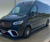 A black Mercedes-Benz van is parked indoors illuminated by soft lighting that highlights its luxury front grille design